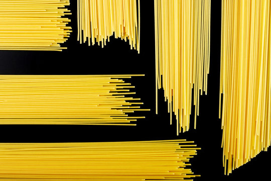 raw pasta, spaghetti on a black background, pattern
