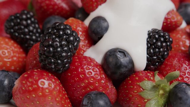 ripe summer berries strawberries, blackberries, blueberries are poured with yogurt