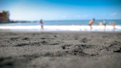Blurred out of focus photo of black volcanic sand on ocean beach