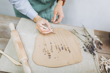 The potter's hands are shaped a cup from a clay. The process of creating pottery. The master ceramist works in his studio. Close-up, only hands. Crockery from clay own hands.	