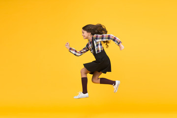 Fototapeta premium Unstoppable future. Happy girl in midair yellow background. Energetic child run to school. Pursuing future goal. Dynamic movement. Childhood and growing up. I will change the future, copy space