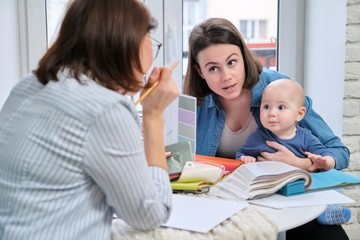 Women interior designer and client with baby choosing fabrics and materials