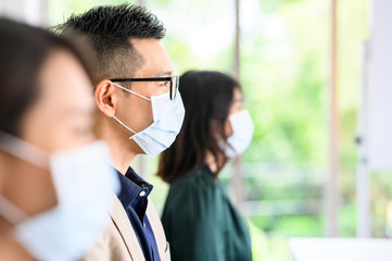 Row of Asian people wear protective face masks for safety and keep social distancing for new normal...