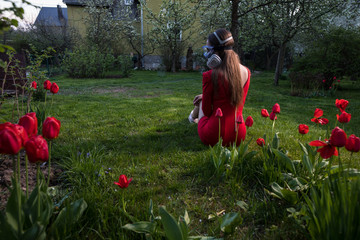 Young beautiful girl portrait in a mask with degree of protection 3M posing in twilight of spring garden.