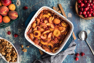 A top down view of a delicious warm stone fruit cobbler cooling on a wooden trivet.