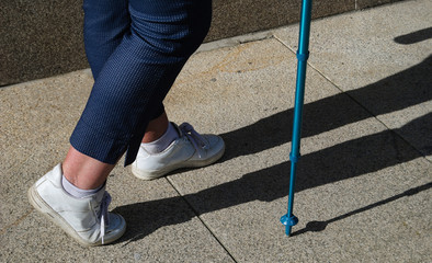 Senhora a caminhar em trilho pedestre com sapatilhas brancas e com vara trecking para maior segurança e equilíbrio
