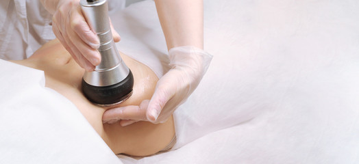 The cavitation procedure closeup. Beautician apparatus for cavitation on the woman's stomach. The concept of skin care face and body