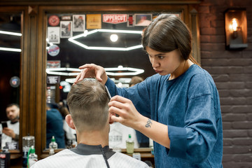 Cool hairstyle. Young caucasian man getting new haircut in the modern barbershop. Professional...