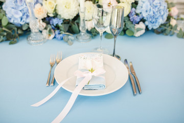 banquet table is decorated with plates, cutlery, glasses, candles and flower arrangements