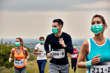 Group of athletes wearing face masks while running marathon in nature.
