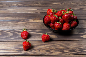 strawberries in a black plate on the table.