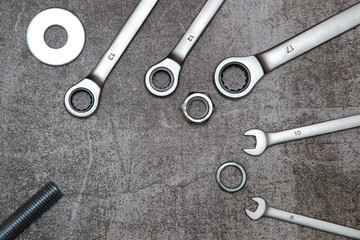 three ring spanners and two ordinary, bolt nut and washers on a gray concrete background.