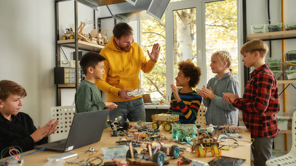 Working process. Young creative male teacher explains for students the principle of robotic...
