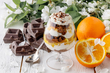 creamy trifle in beautiful glasses and cut fresh ripe fruit on white wooden background - healthy eating concept