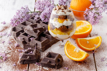 creamy trifle in beautiful glasses and cut fresh ripe fruit on white wooden background - healthy eating concept
