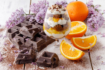 creamy trifle in beautiful glasses and cut fresh ripe fruit on white wooden background - healthy...