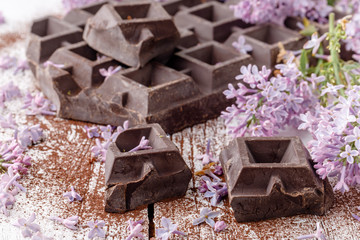 Dark chocolate on table with liliac flowers