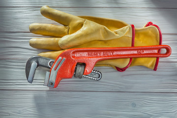 plumbers monkey wrench and yellow leather work gloves on vintage white painted wooden boards