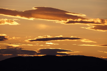 Luminous shades of yellow and orange streak the skies over the Mountains during sunset.