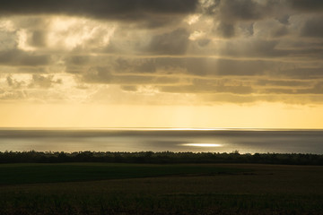 Mysterious sun shining through clouds over Indian Ocean. View at Mauritius beach. December 2016.
