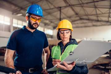 Factory supervisor checking production schedule at CNC machine