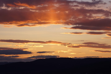 Luminous shades of yellow and orange streak the skies over the Mountains during sunset.