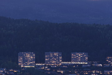 Three Living many storey buildings in front of mountain hill.