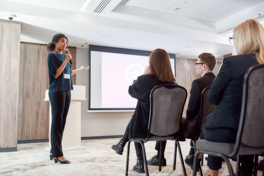 Innovate, Integrate, Motivate. Full-length Shot Of Female Speaker With Microphone Giving A Powerful Talk On Corporate Business Meeting