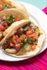 Mexican fish tacos also called Baja with fresh sauce on turquoise background