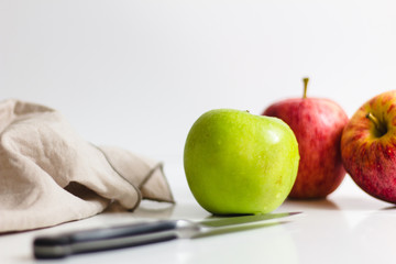 Green and red apple being prepared with knife and being peeled