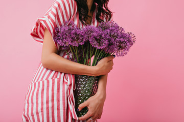Shot of violet wild flowers in vase closeup. Girl in pink sundress holds bouquet