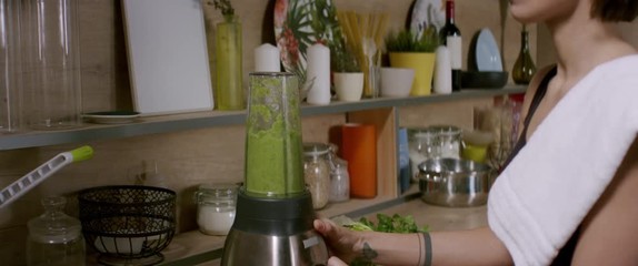 Sporty fit female dancing in the kitchen while preparing green juice tox cocktail. Shot with 2x Anamorphic lens