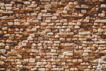Old brick wall texture. Weathered wall surface. Grungy orange brickwall. Red stonewall background. Shabby building facade Italian wall of an old house on sunny day. Vintage backdrop with row brick