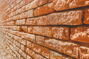 Old brick wall texture. Weathered wall surface. Grungy orange brickwall. Red stonewall background. Shabby building facade Italian wall of an old house on sunny day. Vintage backdrop with row brick