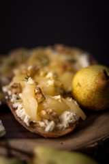 Pear and blue cheese toast with rosemary and honey on a dark and rustic background