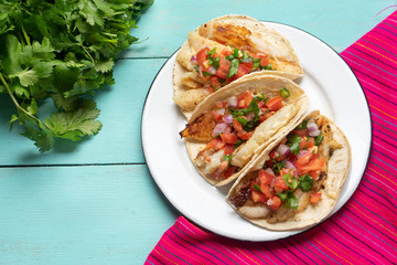 Mexican fish tacos also called Baja with fresh sauce on turquoise background