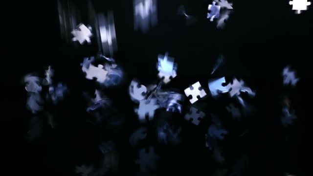 A lot of puzzles from a child's quick-wittedness game fall on a black surface. Closeup. Slow motion. High speed camera