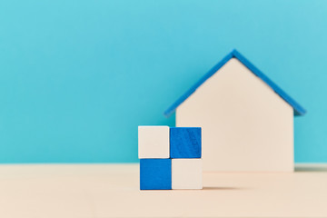 Square of wooden cubes in white, blue colours. Mockup style. Model of house miniature on blurred background, copy space