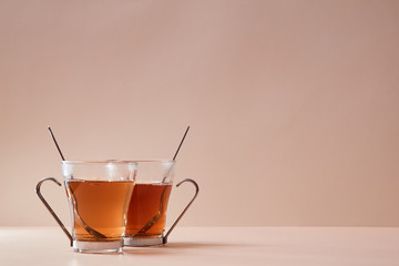 Glass cups with spoons. Tasty traditional english tea. Copy space for text. Pink background. Bun fight concept