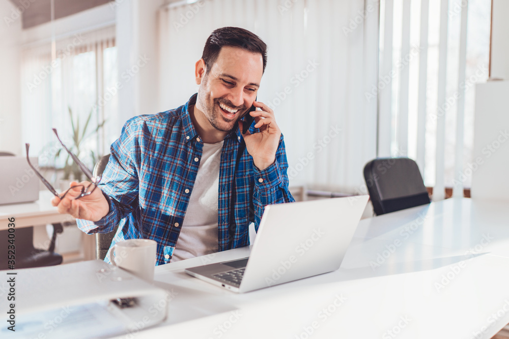 Wall mural businessman sitting at the desk and talking on the phone