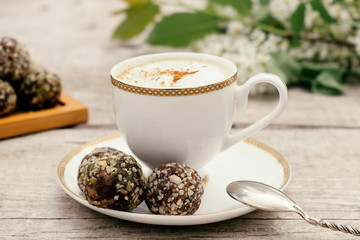 Сup of coffee and protein homemade sweets made from boiled lentils,cocoa powder, peanut paste, dates and decorated with nuts on a wooden background.Сoncept of healthy food and healthy desserts.