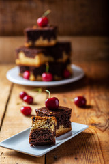 chocolate cake with cherries stacked on a rustic wooden background.