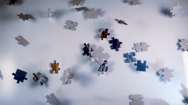 A lot of puzzles from a child's quick-wittedness game fall on a light surface. Closeup. Slow motion. High speed camera