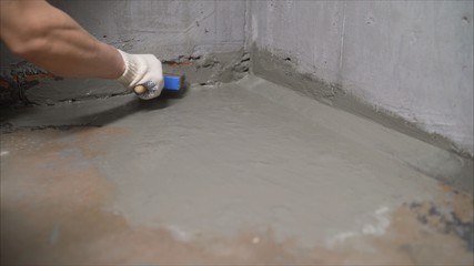 Waterproofing the floor with a brush and mortar. Flooring waterproofing. The master processes the...