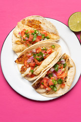 Mexican fish tacos also called Baja with fresh sauce on pink background