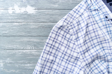 Men's checkered shirt on bright wooden background. Top view. Copy space. 