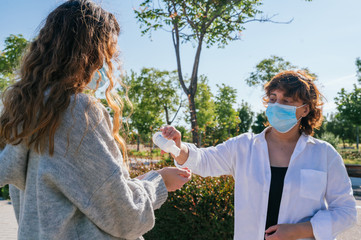 Social distance. Mother pours her daughter disinfectant gel to wash her hands. Mother and daughter in social distancing. Washing their hands. Pandemic. Alcohol disinfectant. Coronavirus. Covid-19.