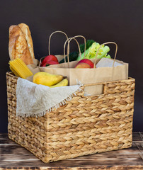 Fresh eco organic vegetables, greens and fruits, cereals and pasta in a wicker basket. Delivery or donation of ecological farm food concept.