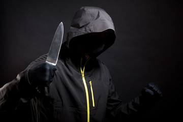 Unknown, indistinguishable bandit in black with knife attacks the victim with a knife. Concept:...