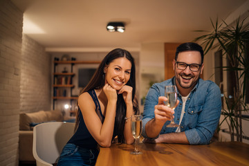 Portrait of a happy couple having a glass of champagne and smiling at camera.